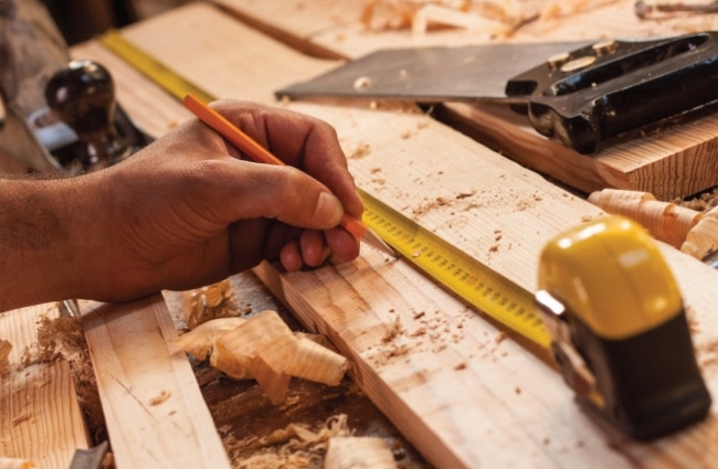 Carpenter cutting and sizing wood for baseboard